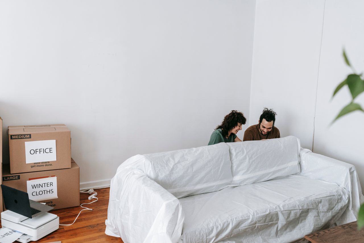 services-04 A couple enjoys moving into a new home, surrounded by boxes and minimalist decor.